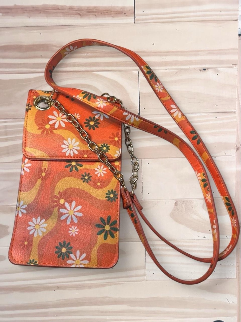 Madden Girl slim crossbody phone bag in orange with a retro floral pattern.